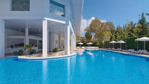 サロウにあるPonient Pirámide Salou by PortAventura Worldの建物の隣にスイミングプール(椅子、パラソル付) +21枚の写真