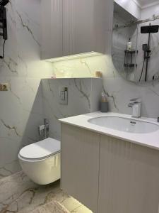 a white bathroom with a toilet and a sink at Tour Lumiere in Bay Tash Tower in Bishkek