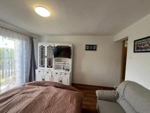 a bedroom with a bed and a tv and a couch at LídRind porta in Zalaszentgrót