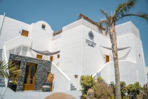 a white building with a palm tree in front of it at Divino Caldera in Akrotiri