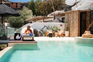 a man sitting in a chair next to a swimming pool at Divino Caldera in Akrotiri