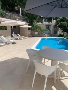 a table and chairs next to a pool with an umbrella at REZEVICI BOUTIQUE VILLA in Petrovac na Moru