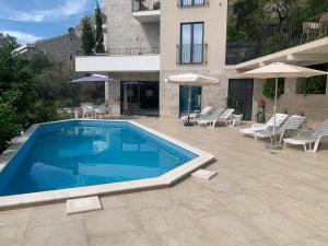 a swimming pool with chairs and umbrellas next to a building at REZEVICI BOUTIQUE VILLA in Petrovac na Moru