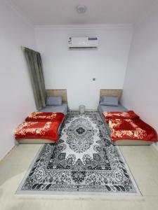 two beds in a room with a carpet on the floor at مناهل للغرف in Dammam