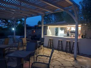 a patio with tables and chairs and a bar at night at Vour 52 in Vourvourou