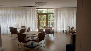 Un comedor con mesas y sillas y un gran ventanal. en Novo studio sofisticado ao lado do Allianz Parque, en São Paulo