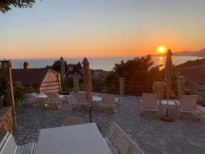 a sunset over a patio with chairs and umbrellas at REZEVICI BOUTIQUE VILLA in Petrovac na Moru