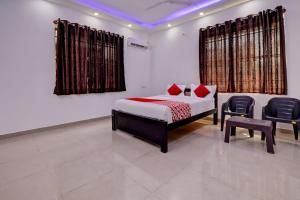 a bedroom with a bed and chairs in a room at Hotel O Maruthi Paradise Netaji Udyanavana Park in Bengaluru +23 photos