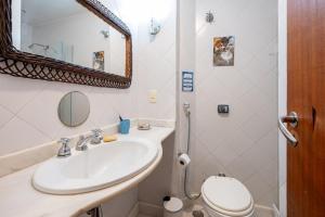 a bathroom with a sink and a toilet and a mirror at 2 quartos a 200m da Praia do Flamengo in Rio de Janeiro