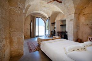 a bedroom with a large bed in a stone wall at Masseria Guadalupe, The Mascienda in Ostuni +156 photos