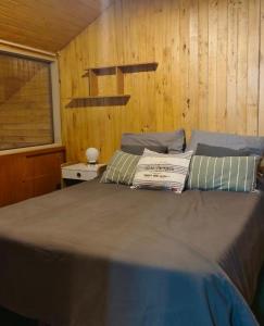 a bed in a room with a wooden wall at Depto 5 pax, 2 baños, Cirrus 967 in Las Lenas +10 photos