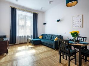 a living room with a blue couch and a table at Golden Market Square Apartments by Tyzenhauz in Kraków