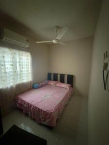 a bedroom with a pink bed and a ceiling fan at Homestay Jawahir in Mentekab
