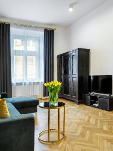 a living room with a vase of yellow flowers on a table at Golden Market Square Apartments by Tyzenhauz in Kraków +18 photos