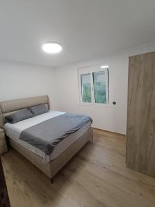 a white bedroom with a bed and a window at ApartmaniMD apartman 5 uzivanje na pravom mjestu in Sutomore