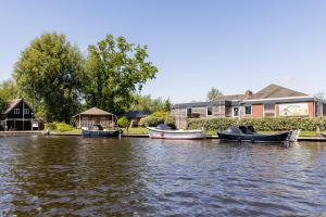 ヘーグにあるWaterherberg It Beakenの3隻のボートが家の隣の水上に停泊している