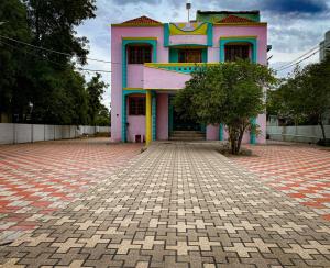 een roze gebouw met een boom ervoor bij Butterfly Blossom Villa in Samayapuram