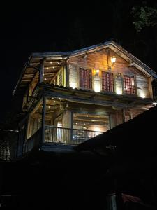 a large wooden house with lights on it at night at Whispering Pines Villa in Peje