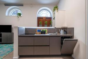 a kitchen with a counter with a sink and two windows at Appartamento Al Vecchio Tram in Udine