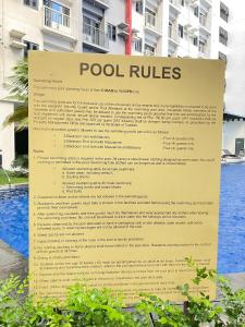 Un cartel que dice las reglas de la piscina frente a un edificio. en SMDC BLoom Condo Tower A Unit 415, en Sampong