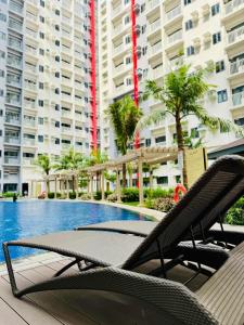una piscina con 2 tumbonas frente a un edificio en SMDC BLoom Condo Tower A Unit 415, en Sampong