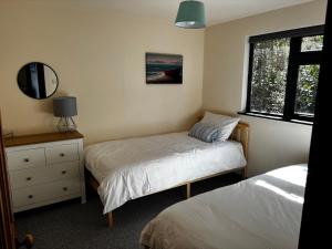 a bedroom with two beds and a dresser and a window at Northfield Holiday Park in Borth