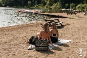 two women sitting on a towel on the beach at Le2089 - Spa et plage - Les chalets dans le nord in Sainte-Lucie-de-Doncaster