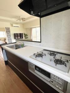 a kitchen with a stove and a sink at アラハブルーリゾート in Chatan