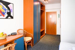a room with a desk and a bed and a table at Vinetahotel Stadt Barth in Barth