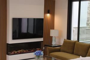 ein Wohnzimmer mit einem Sofa, einem TV und einem Kamin in der Unterkunft Casa Rural La Tajuela in Bohonal de Ibor