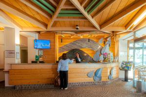 a woman standing at a counter in a restaurant at Hotel Les Vallées Labellemontagne in La Bresse