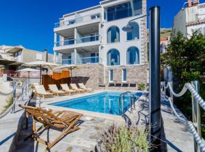 Una piscina con sillas y un edificio. en Apartments Villa Capitano, en Mlini
