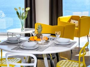 Un comedor con una mesa blanca y sillas amarillas. en Apartments Villa Capitano, en Mlini