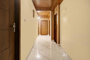 a hallway with white tile and a wooden door at Townhouse Kachighati Formerly Palm Bliss in Shimla