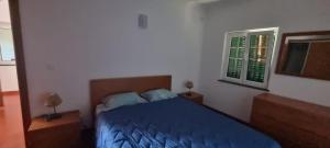 a bedroom with a blue bed and a window at Quinta do José - AL in Praia da Vitória