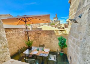 eine Terrasse mit Sonnenschirm und Tisch und Stühlen in der Unterkunft Maison de Roche - Uzès Centre historique La Fenestrelle in Uzès
