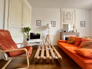 a living room with an orange couch and a tv at Magnifique T3 en plein centre ville de Poitiers in Poitiers