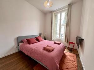 a bedroom with a large bed with pink sheets and a window at Magnifique T3 en plein centre ville de Poitiers in Poitiers