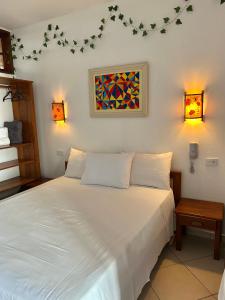 a bedroom with a white bed with two lamps at Pousada e Residencial Villafranca in Boicucanga