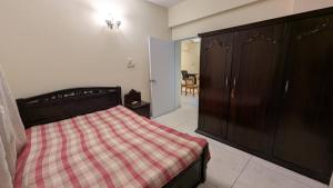 a bedroom with a bed with a checkered blanket at Room in Uttara Sector 3 Apartment in Bāiljuri