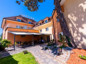 a building with a patio with tables and umbrellas at Hotel Tulipan Pruhonice in Pruhonice