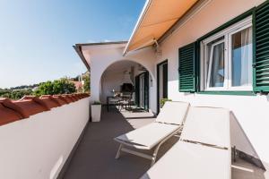 a balcony with white chairs and green shutters at Apartment Eva in Murter