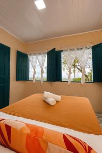 a bedroom with a bed with green cabinets and windows at Suítes Benfica in Arraial d'Ajuda