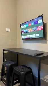 a desk with a television on a wall with stools at Suíte 05 • Praia das Pitangueiras in Guarujá