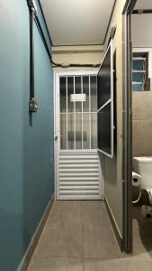 a bathroom with a door and a toilet in a room at Suíte 05 • Praia das Pitangueiras in Guarujá