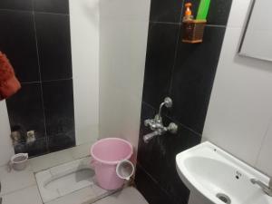 a bathroom with a sink and a pink bucket at Family Room in Indore +5 photos