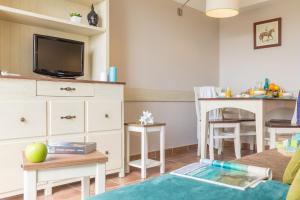 a living room with a tv and a dining room at Village Pierre & Vacances Normandy Garden in Branville