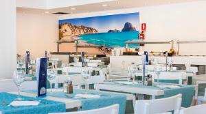 a dining room with white tables and white chairs at Globales Montemar in Cala Llonga