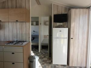 a kitchen with a white refrigerator and a sink at Camping des Hautes Grées in Erquy