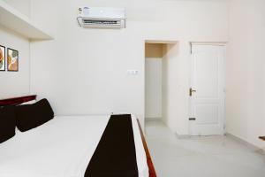 ein weißes Zimmer mit einem Bett und einer Tür in der Unterkunft Super Collection O Sholinganallur Chennai Formerly Nimalan Residenc in Chennai